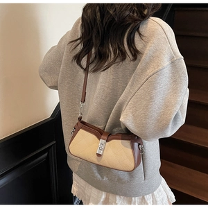 Detalle de bolso bandolera acolchado beige con ribete de cuero marrón y cierre de metal