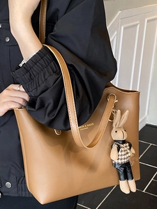 Elegant brown leather tote bag with gold lettering and a cute bunny pendant charm