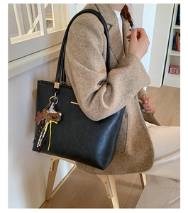 Close-up of black PU leather tote bag with a cute brown bear charm for casual daily use