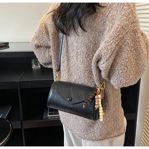 Detail view of black vintage leather crossbody bag with wooden beads and gold hooks