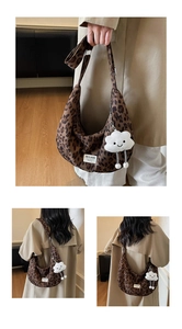 Detail of leopard print crescent bag with plush cloud charm and adjustable canvas strap