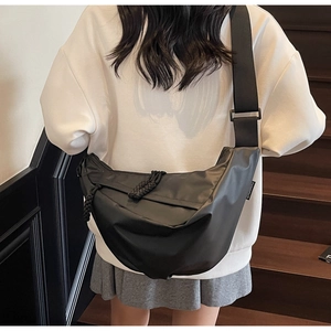 Detail view of black crescent crossbody bag with nylon strap and woven zipper pull