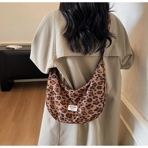 Close-up of leopard print crescent hobo bag with logo patch on model's shoulder