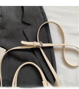 Detail view of beige crossbody bag showing adjustable shoulder strap with silver buckle