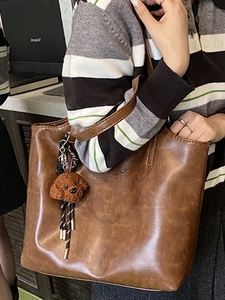Brown faux leather tote bag with New Bag Paris logo and plush poodle charm on a model