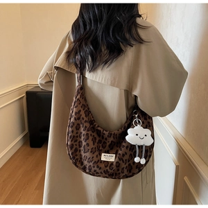 Close-up of leopard print canvas crescent bag with a white plush cloud charm detail
