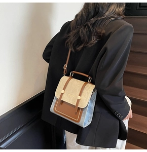 Detail of vintage three-tone handbag with denim and brown leather accents on person