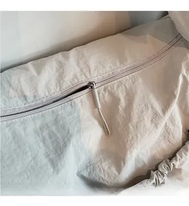 Detail view of smooth zipper closure on light gray nylon shoulder bag with long puller
