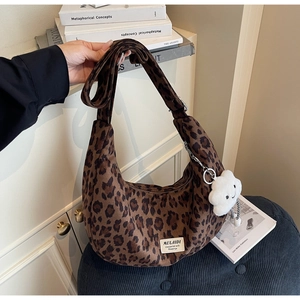 Detail of leopard print crescent bag featuring soft suede texture and plush cloud charm