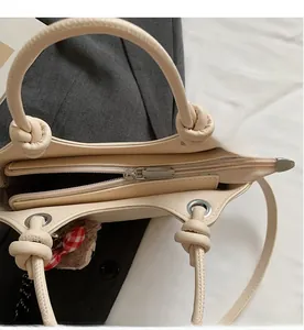 Top view of cream handbag showing smooth zipper closure and plush bear charm detail