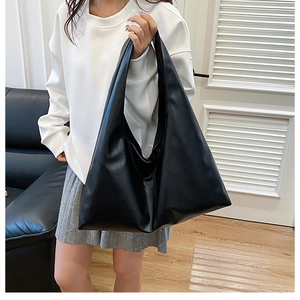 Close-up of minimalist black PU leather tote bag showing smooth matte texture and soft drape