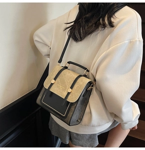 Detailed shot of a vintage small square bag with rivets on a model in a modern stairway