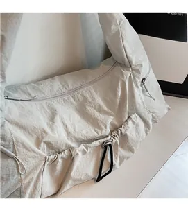 Detailed close-up of light grey nylon shoulder bag with pleated texture and drawstring