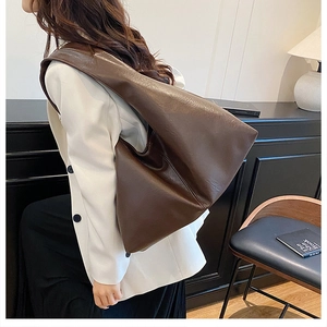 Model wearing dark brown soft leather tote bag with a minimalist large capacity design