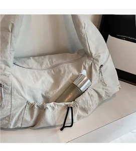 Detail view of light grey nylon crescent bag showing large capacity with a water bottle