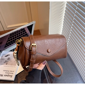 Close-up of a brown retro crossbody bag with wooden bead charm and glossy leather finish