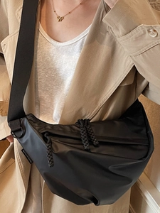 Modern black nylon crescent crossbody bag with woven zipper and wide shoulder strap