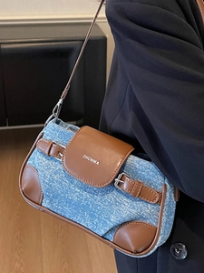 Chic blue denim shoulder bag with brown leather trim and metallic brand logo