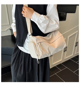Detail of off-white cylindrical tote bag with nylon texture and side zipper pocket