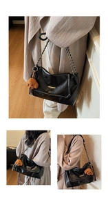 Detail of black faux leather tote with golden bar trim and brown plush bear charm
