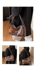 Detail view of dark brown tote bag with chain strap and cute plush dog charm