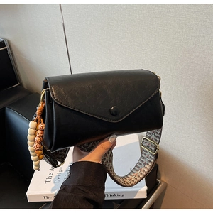 Detail of black retro crossbody bag with triangle flap and geometric woven strap