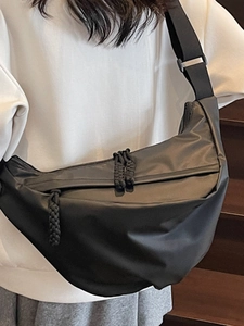Chic black crescent crossbody bag in matte nylon shown from a side view on a model