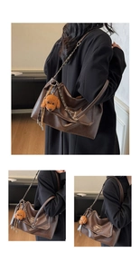 Detail view of brown vintage leather tote with chain strap and teddy bear pendant