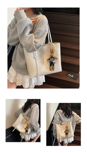 Dettaglio della borsa tote in pelle PU bianco crema con ciondolo a coniglio e scritte