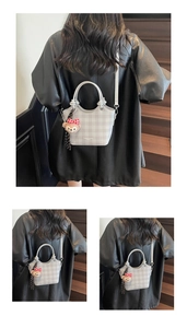 Close-up of a light grey checkered tote bag featuring a cute plush bear charm on stairs