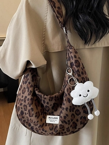 Chic leopard print tote bag with plush cloud charm shown on shoulder with beige trench coat