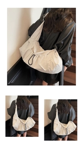 Detail of off-white crossbody bag with drawstring closure and adjustable strap on model