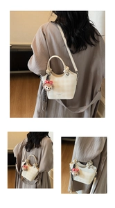 Close-up of cream plaid crossbody bag with cylinder handles and plush bear charm detail