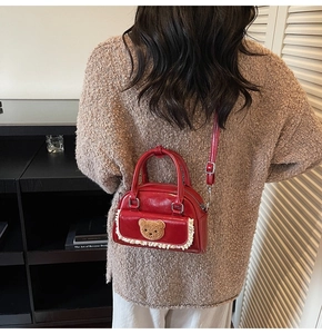 Detail of red mini square bag with cute bear charm and lace trim on a cozy sweater