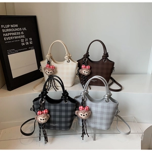 Detail of four stylish bucket bags in solid and checkered patterns with plush charms