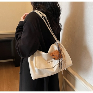 Detail of off-white tote bag with textured faux leather, metal clasp and cute plush dog charm