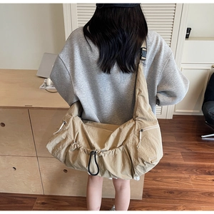 Detail shot of khaki nylon shoulder bag with drawstring closure and multiple zip pockets