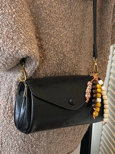 Minimalist black envelope crossbody bag with colorful ethnic beaded charm and slim strap