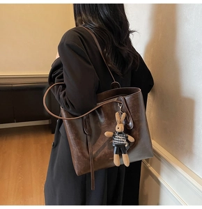 Dettaglio della borsa tote vintage marrone caffè con un ciondolo a forma di coniglio soffice