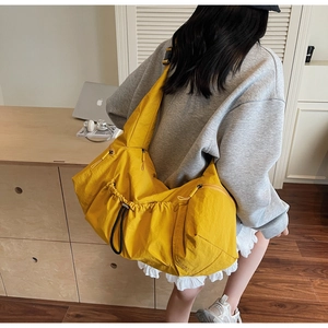 Detail view of large yellow nylon tote bag featuring side drawstring pocket and zipper