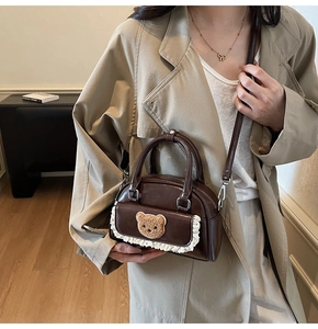 Detail of dark brown mini crossbody bag with cute bear embroidery and white lace trim