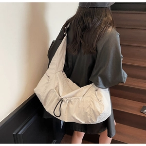 Detailed close-up of large cream-colored nylon tote bag with drawstring on a model