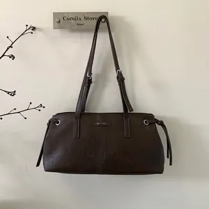 Dettaglio della borsa tote in pelle PU marrone scuro con lacci decorativi e logo del marchio