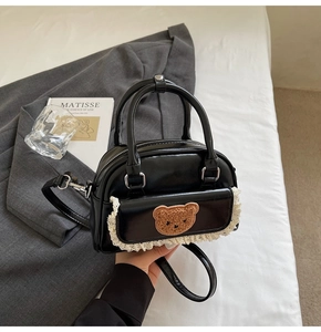 Close-up of black PU leather bag with cute plush bear patch and delicate lace trim detail