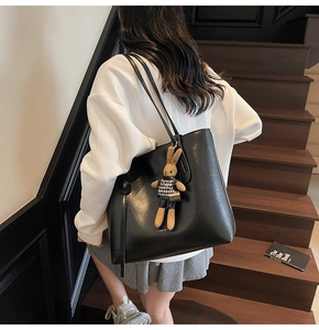 Dettaglio della borsa tote nera con un ciondolo a forma di coniglio sulla tracolla moda
