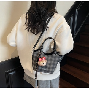 Macro detail of checkered crossbody bag with plush Duffy bear charm and round handles