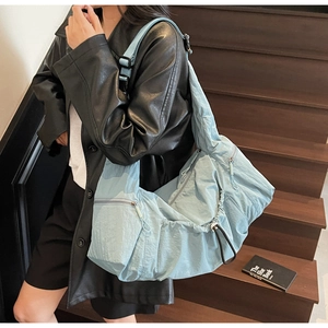Detail of adjustable strap and drawstring closure on large blue nylon crescent tote bag
