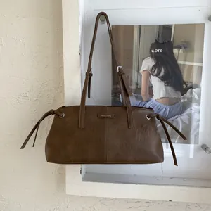 Dettaglio di borsa marrone vintage con nappe laterali e placca con logo argentato