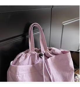 Detail of light purple waterproof nylon backpack showing reinforced handles and drawstring