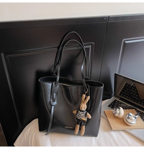 Dettaglio della borsa tote in pelle PU nera con ciondolo a coniglio e laptop in ufficio